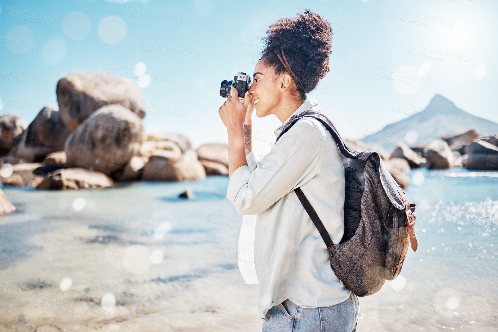 Buy stock photo Photography camera, ocean and photographer shooting outdoor beach, sea or nature beauty picture. Blue sky flare, peace or sunshine freedom for tourist black woman on summer travel adventure in Brazil