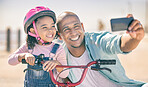 Dad, girl and bike for selfie, smile and park in sunshine, safety or happiness together with phone. Father, kid and bicycle for digital photo, smartphone or happy family with bonding, love or outdoor