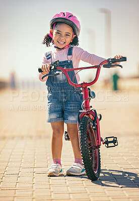 Girl, bike training and portrait, learning development and sports in street outdoor. Young child, bicycle safety with helmet and smile for fitness exercise, happiness and fun in summer sunshine