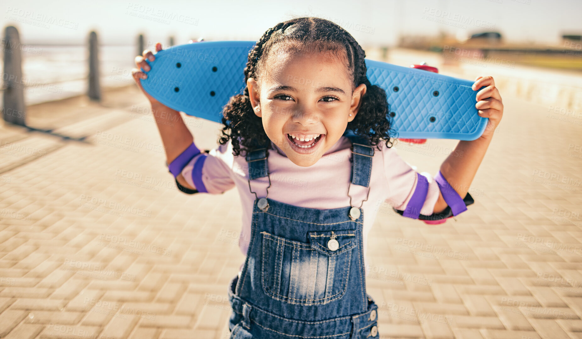 Buy stock photo Child, skateboard and excited for fun activity outdoor on promenade with smile, happiness and energy on summer vacation. Portrait of black girl with safety gear for elbow for skating or skateboarding