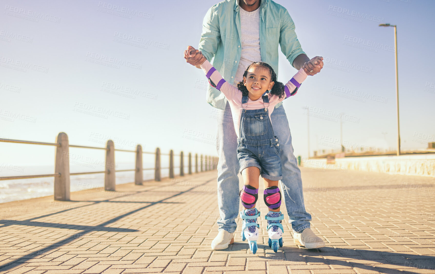 Buy stock photo Girl, dad and park for skating, learning and hands to hold for balance, care and safety on concrete. Father, child and roller skates with teaching in urban, ocean promenade or walk in summer sunshine