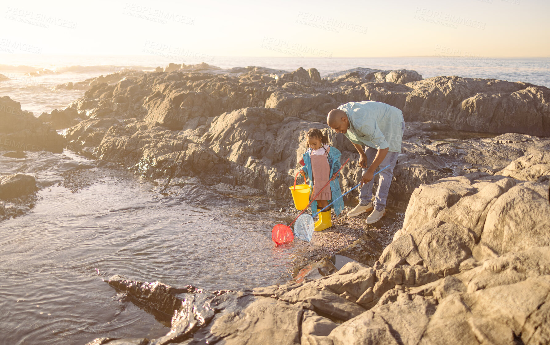 Buy stock photo Family, children and beach with a father and daughter bonding by a rock pool during summer together. Kids, fishing or love with a man and girl playing in the water with a net and bucket for fun