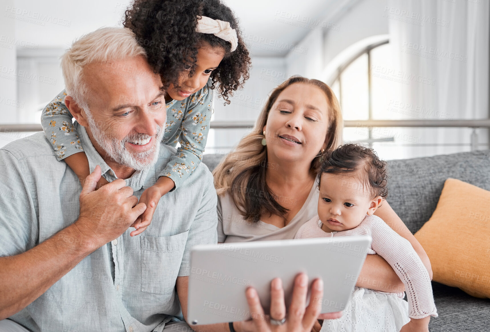 Buy stock photo Relax, tablet and grandparents with children on sofa for movie, cartoon or educational app online. Grandmother, grandpa and kids streaming entertainment in interracial family home in Mexico.

