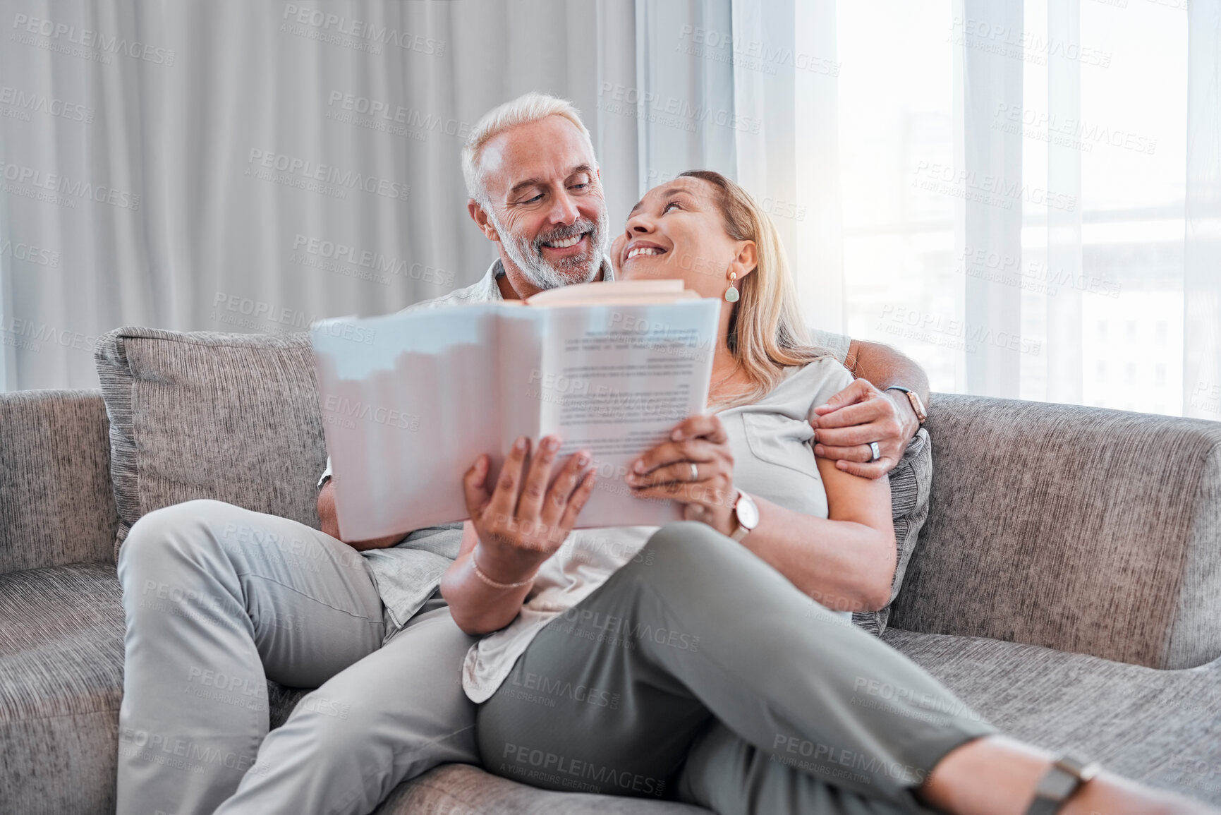 Buy stock photo Book, reading and relax with a senior couple sitting on a sofa in the living room of a home together. Books, love and storytelling with a mature man and woman enjoying a read while bonding in a house