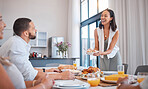 Family, friends and woman serving lunch for celebration of Christmas, birthday or weekend time. Happy family, men and women smile at table eating and drinking together at dinner with home cooking.