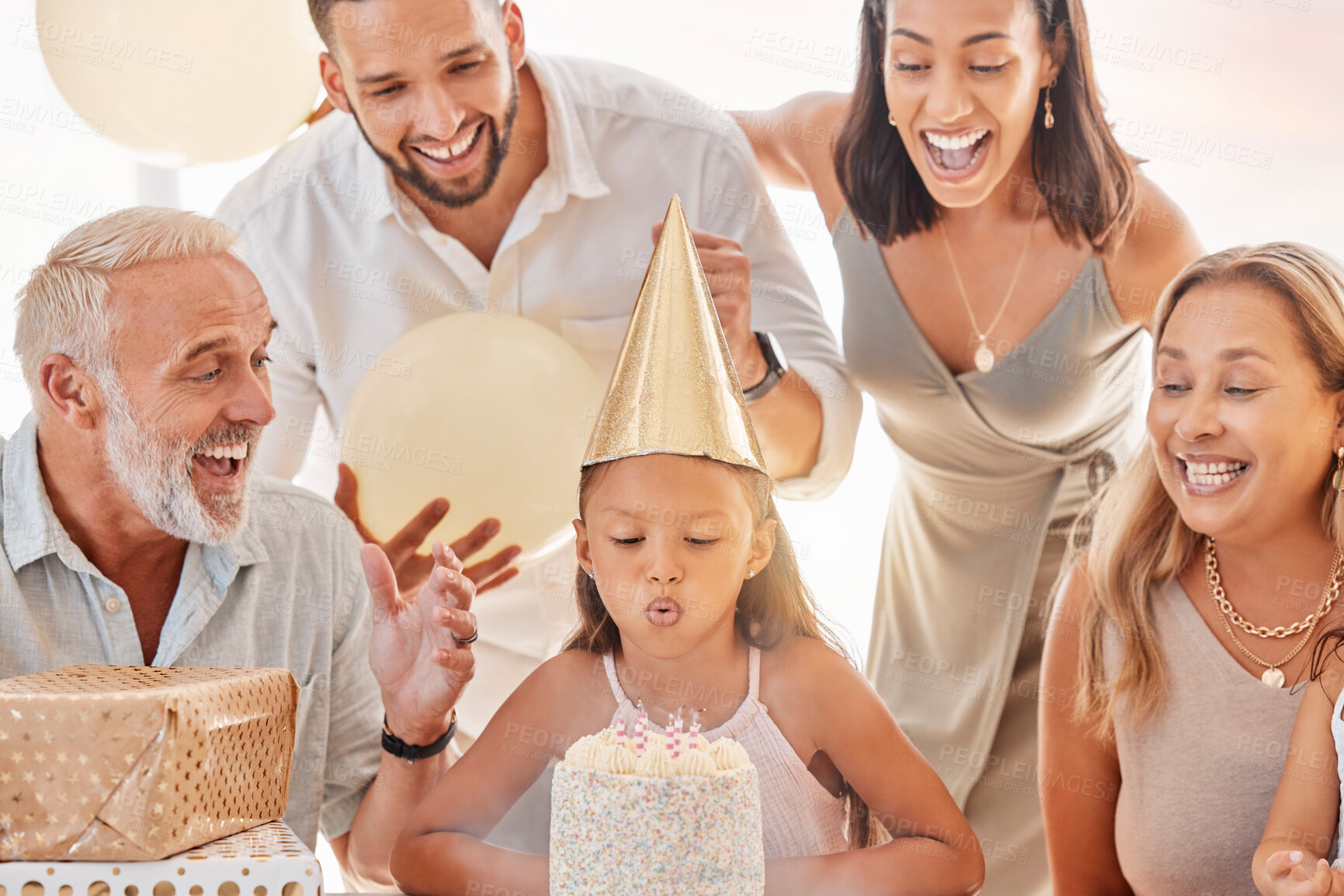 Buy stock photo Birthday cake, blow candle and family celebration, party and singing with decorations, event and gift in home. Happy birthday, birthday party or candles for girl with parents, grandparents or balloon