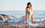 Yoga, fitness and woman at the beach for exercise while in cobra pose for breathing, zen and wellness on rock while on vacation in summer. Female by sea to meditate, workout and practice mindfulness