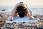 Yoga, meditate and fitness with a woman on a rock at the beach for mental health, wellness or exercise. Training, workout and meditation with a female athlete stretching outdoor in nature for health