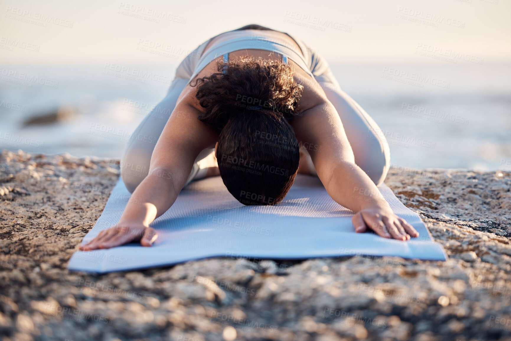 Buy stock photo Yoga, meditate and fitness with a woman on a rock at the beach for mental health, wellness or exercise. Training, workout and meditation with a female athlete stretching outdoor in nature for health