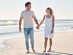 Couple, holding hands and walking on the beach for love, care or relationship bonding together in the outdoors. Happy man and woman relaxing on a lovely walk on the sandy ocean coast for romance