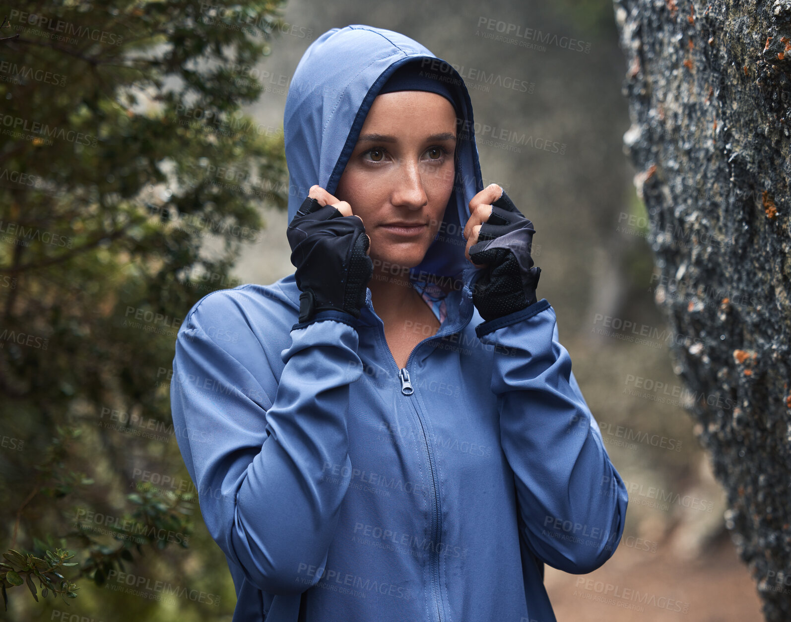 Buy stock photo Woman, hiking and forest with rain on adventure, travel and explore nature on winter vacation. Girl, hiker and hoodie for safety in woods, cold or weather by trees, hiking trail or walk for fitness
