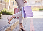 Shopping bag, woman customer and city street for retail fashion, clothes or luxury. Discount, sale and summer choice of girl shoes, legs and feet lifestyle walking with paper bag for rich or wealth
