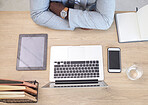 Laptop, tablet and phone with a business man sitting at his desk in the office at work from above. Flatlay, computer and technology with a male employee working on a table or wooden surface