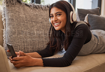 Buy stock photo Woman, happy and headphone phone music of a person listening to a podcast or video watching at home. Portrait of an indian person with happiness and smile about mobile technology on living room sofa