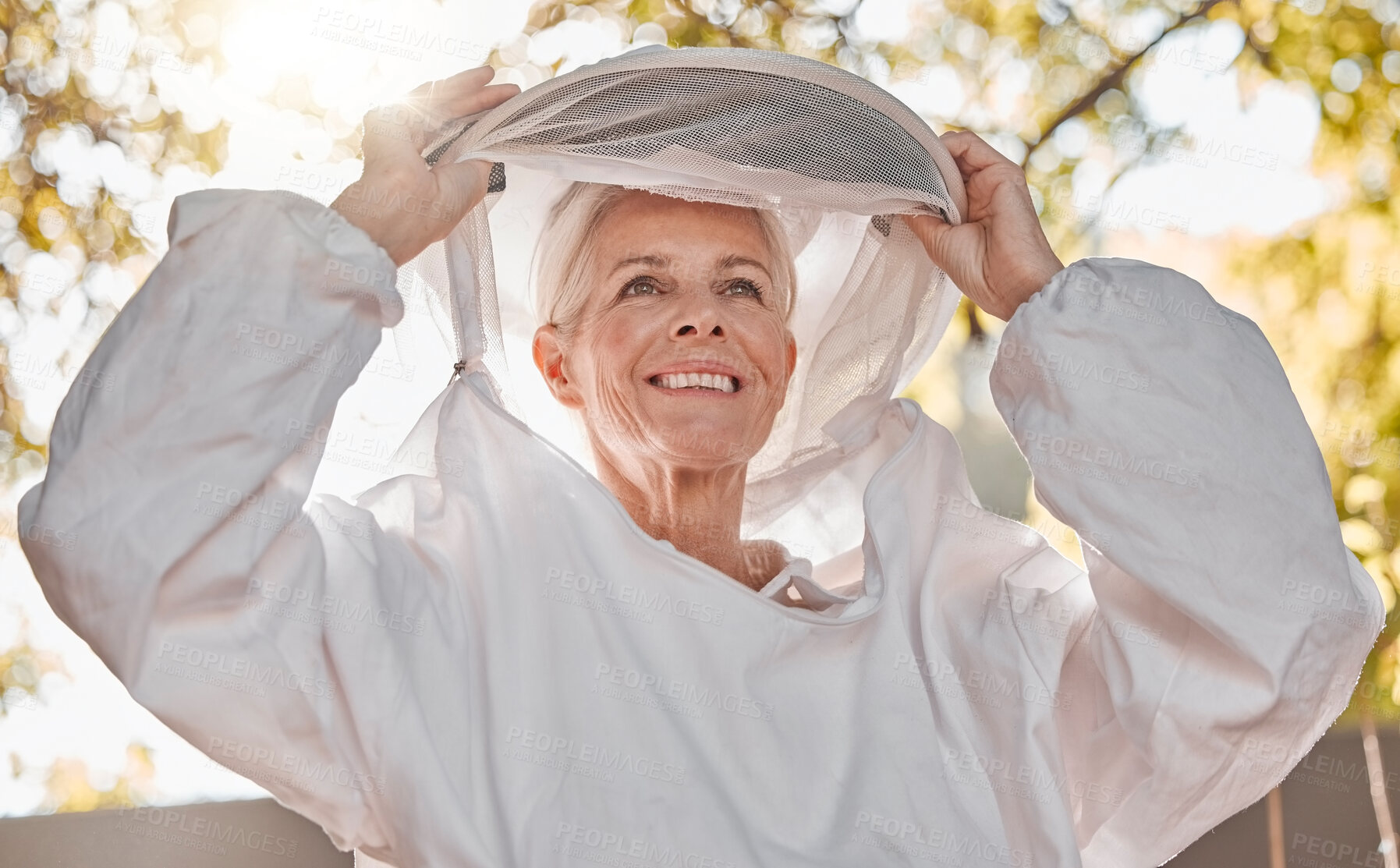 Buy stock photo Happy, beekeeper and woman in nature for honey collection, monitor beehive health or check backyard environment. Smile, agriculture and senior apiarist in safety gear ready to start garden inspection