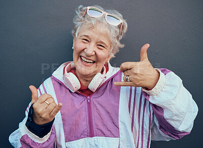Buy stock photo Shaka sign, portrait and senior woman in retirement standing by gray wall with a smile or happiness. Happy, fun and friendly elderly lady pensioner in the outdoor city with a hang loose hand gesture.
