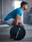 Fitness, deadlift and man in gym in a workout, exercise or strength training for strong powerful legs and core. Focus, wellness and healthy Indian sports bodybuilder weightlifting a heavy barbell 