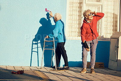 Buy stock photo Senior women, friends and spray paint for vandalism, graffiti and street art drawing on nursing home building wall. Crazy old people break law with illegal pop art outdoor in retirement for fun