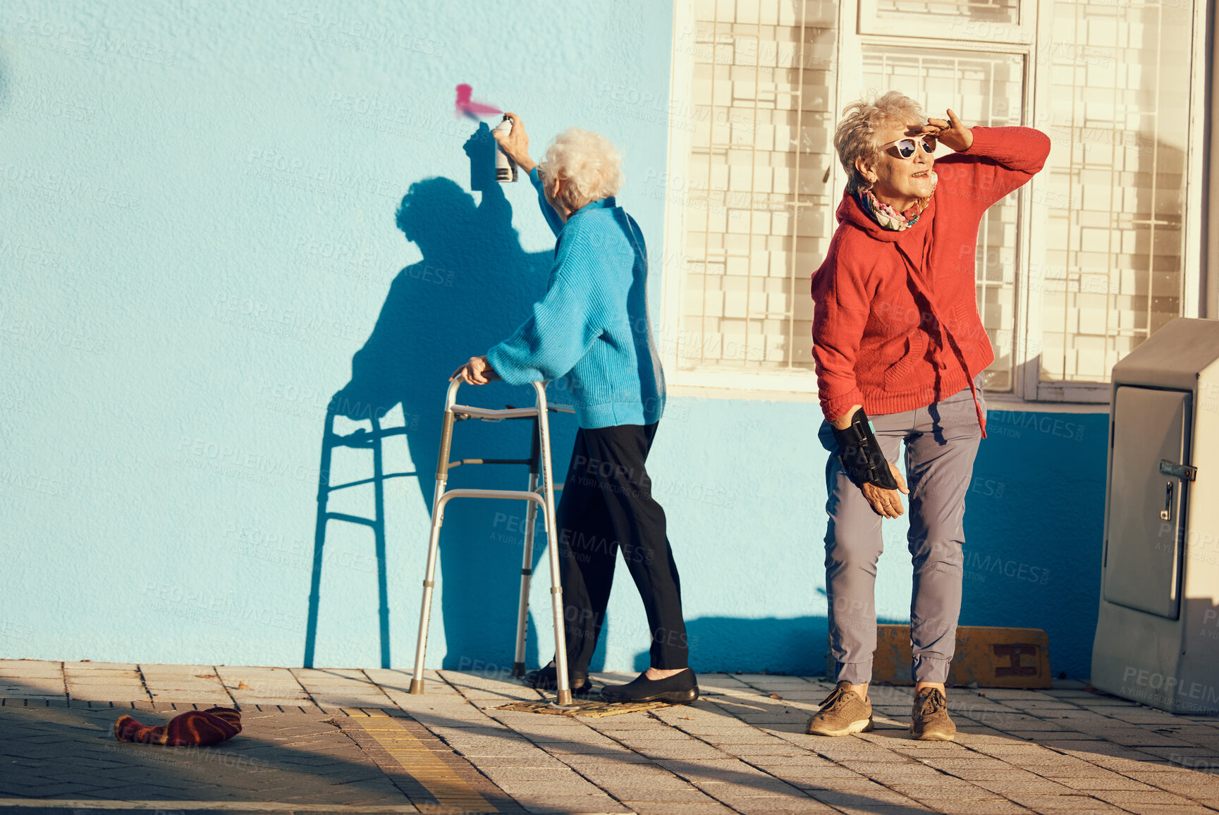 Buy stock photo Senior women, friends and spray paint for vandalism, graffiti and street art drawing on nursing home building wall. Crazy old people break law with illegal pop art outdoor in retirement for fun