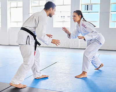 Buy stock photo Karate, martial arts and man and woman fight, battle or practice fighting skill during training, workout or fitness challenge. Coach, dojo class and girl learning self defense from taekwondo teacher