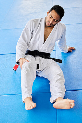 Sports, injury and pain in legs on karate fitness dojo floor for tournament, training or workout. Professional athlete uniform of martial arts man with knee pain or arthritis at sport club.