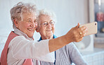 Phone, happy and elderly friends smile for pictures to share on social media online while relaxing in retirement. Happiness, love and senior women smiling while enjoy quality time at home in Berlin