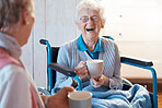 Senior woman, friend and coffee or tea while in a wheelchair for a disability or rehabilitation and happy or laughing about funny conversation or joke. Old people together for fun in nursing home