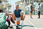 Sports, basketball and friends, men relax and fist bump on basketball court in happy summer. Friendship, teamwork and basketball player sitting on ground with friend and ball in community playground.