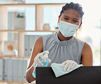 Covid, mask and sanitizer with a business black woman cleaning her computer and office equipment at work. Portrait, sanitizing and wipe with a female employee during the corona virus pandemic