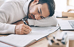 Bored, writing and diary with a business man lying on his desk at work while making note of an appointment. Schedule, calendar and notebook with a male employee working on an idea while feeling tired