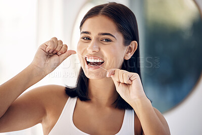 Smile, woman in bathroom flossing teeth and morning dental care routine in home mirror. Health, wellness and Indian woman with dental floss, motivation for cleaning for healthy mouth and fresh breath