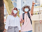 Covid, travel and tourism with a muslim couple pointing while sightseeing outdoor overseas or abroad. Tourist, mask and honeymoon with an islamic man and woman traveling in the corona virus pandemic