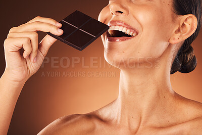 Buy stock photo Beauty, chocolate and beauty woman, skincare and happy smile, eating andsmile on brown studio background. Young female face, bite and dark chocolate bar, cocoa candy and calories with delicious food