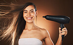 Beauty, hair and hairdryer with a model woman in studio on a brown background for blowdrying or treatment. Portrait, haircare and style with an attractive young female drying or styling her locks