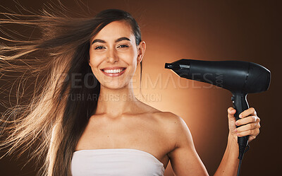 Buy stock photo Beauty, hair and hairdryer with a model woman in studio on a brown background for blowdrying or treatment. Portrait, haircare and style with an attractive young female drying or styling her locks
