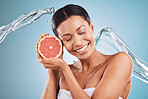 Grapefruit, black woman and water for skincare, cosmetics and hygiene with blue studio background. Citrus, young female and girl with smile, body care or natural beauty to relax, smooth or clear skin