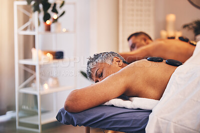 Relax, massage and hot stone with a couple in a spa, lying on a table or bed for physical therapy. Rock, sleep and luxury with a senior mand and woman in a health or wellness center for stress relief
