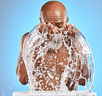 Water splash, black man and facial skincare on blue background for shower, wellness and clean body care with personal hygiene. Male beauty, studio model and washing face with water drops in bathroom