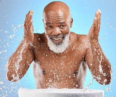 Buy stock photo Water splash, senior and black man cleaning face in studio isolated on a blue background. Skincare, hygiene and retired elderly male from Nigeria bathing or washing for wellness and healthy skin.