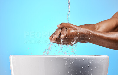 Buy stock photo Clean, water and man washing his hands for hygiene, to stop germs and prevent bacteria in a studio. Wellness, health and closeup of a guy cleaning his hand by a basin isolated by a blue background.