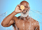 Man face, fruit or water splash on blue background in studio for vitamin c treatment, healthcare wellness or cleaning hygiene. Portrait, smile happy or mature skincare for black model with wet lemon
