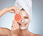 Woman, skincare and mask with grapefruit, smile or happy in studio for wellness, self care or beauty. Model, skin and cream for soft glow with facial, fruit and happiness by grey studio background