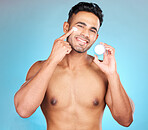Portrait, skincare and man in studio with face cream for wellness, pamper and cleaning on blue background. Face, beauty and facial, mask and product on guy model relax,  luxury and grooming mockup