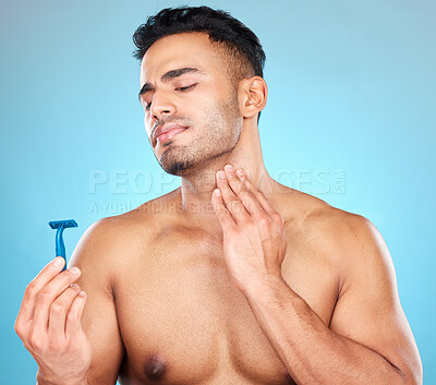 Buy stock photo Skincare, shaving and man with razor in studio on blue background for wellness, beauty and self care. Grooming, facial treatment and male face with worry, concern and anxiety to shave sensitive skin