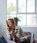 Beautiful woman looking out window using smartphone holding cup of coffee relaxing at home
