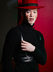 Portrait, fashion and stylish man with vitiligo posing on a red studio background looking confident. Confidence, face and trendy or edgy man with fashionable clothing and hat on an apparel backdrop
