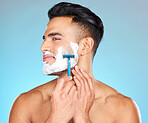 Studio, skincare and model shaving beard with razor blade for beauty wellness, grooming or self care on blue background. Hair removal, face or man cutting facial hair in morning routine with product 