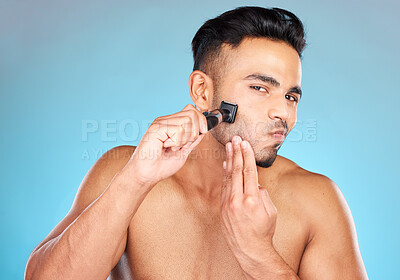 Buy stock photo Man, shave and razor for wellness, skincare and cosmetics against blue studio background. Indian male, beard and shaver for natural beauty, smooth and clear skin for treatment, routine and grooming.