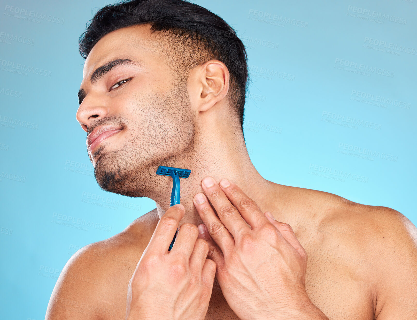 Buy stock photo Man shaving, razor and grooming beard or facial hair for self care, skincare and body wellness on blue studio background. Face of indian model with a smile for clean shave, cosmetics and healthy skin
