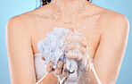 Woman, shower and hands with sponge close up or body cleaning or washing for skincare hygiene in studio. Model, skincare cleaming and foam sponge for cosmetics scrub or  body care in blue background